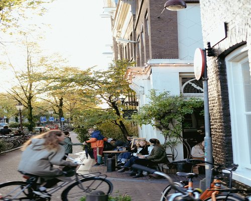 Two friends sitting at an outdoor cafe with their bikes parked nearby